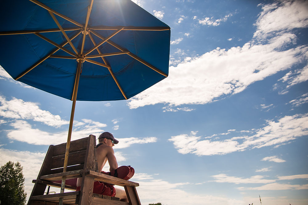 Young male lifeguard on watch under sun umbrella